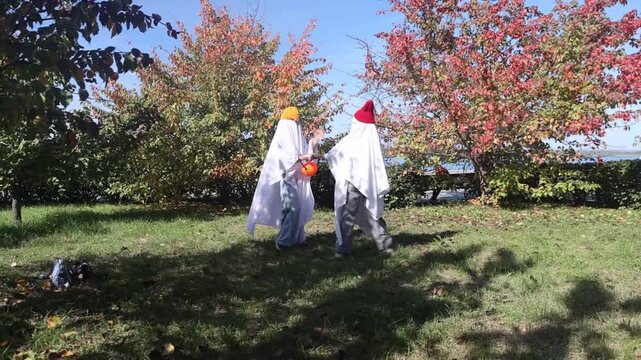 two kid in Halloween ghost costumes Wearing bright hats and black glasses,  in the park. Halloween party