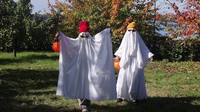 two kid in Halloween ghost costumes Wearing bright hats and black glasses,  in the park. Halloween party