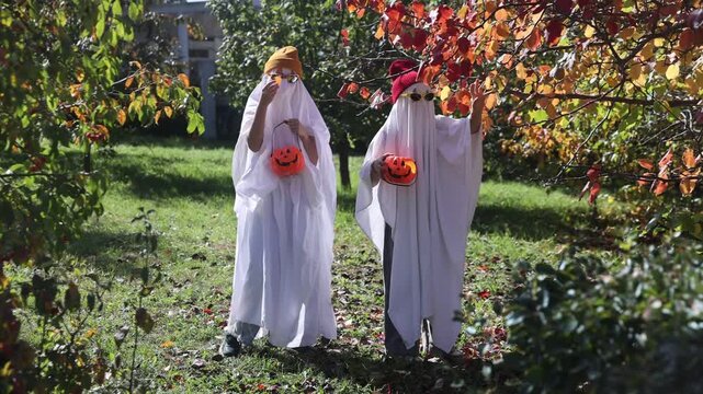 two kid in Halloween ghost costumes Wearing bright hats and black glasses,  in the park. Halloween party