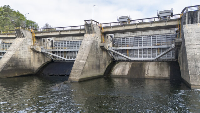 Aerial view of the Velle Dam on the Mino River, featuring concrete spillway gates, steel structures, and flowing water in Ourense, Ourense, Spain.