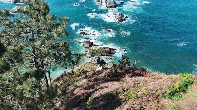 Aerial drone shot moving forward from cliff edge to reveal ocean rocks and turquoise sea