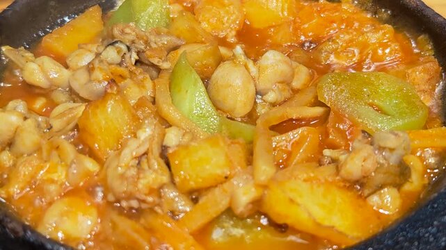 Close-up top-down view photograph of a cooked bullfrog pot with celtuce and potato