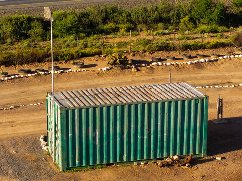 Aerial view of a green shipping container placed in a dirt lot in Ladismith, Western Cape, South Africa.