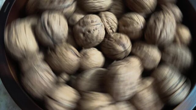 pile of walnuts in shell rotating on a wooden bowl video