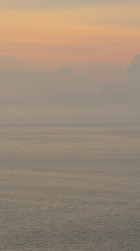Peaceful sunset over the sea with distant boats and hazy sky in Pattaya, Thailand