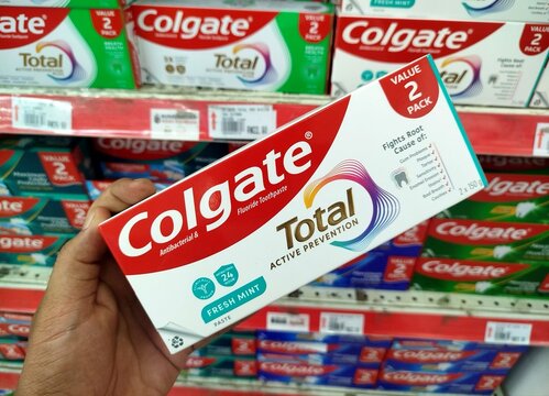 KUALA TERENGGANU MALAYSIA- OKTOBER 08. 2026: Hand holding a Colgate Total toothpaste value pack in a store aisle, showcasing product branding, packaging design, and oral care concept.
