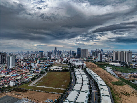 Aerial view of the cityscape of Phnom Penh with modern skyscrapers, urban infrastructure, and a dramatic cloudy sky in Phnom Penh, Phnom Penh, Cambodia.