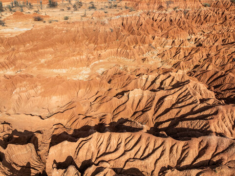 Aerial view of Tatacoa Desert red desert showing intricate eroded clay formations and gullies under bright sunlight in Villavieja, Huila, Colombia.