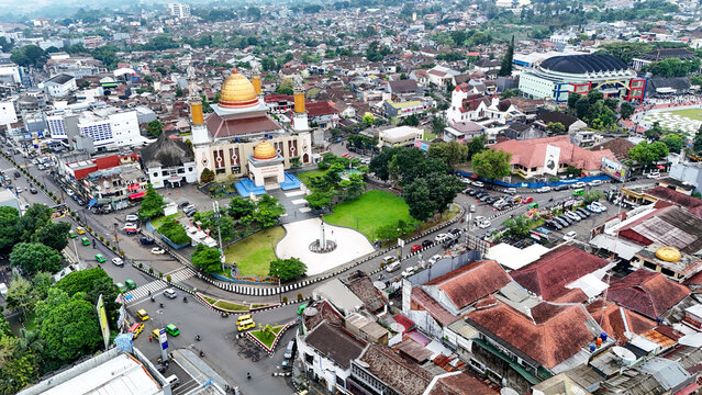 Aerial view of Masjid Agung Kota Sukabumi with its golden dome and minarets, surrounded by urban rooftops, green spaces, and busy streets in Sukabumi, West Java, Indonesia.
