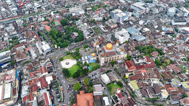 Aerial view of Masjid Agung Kota Sukabumi with its golden dome, surrounded by dense urban rooftops, streets, and green spaces in Sukabumi, West Java, Indonesia.