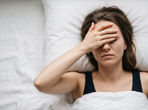 Young woman severe migraine headache covering eyes with hand