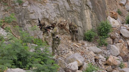 Fototapeta premium Special forces soldiers patrol through treacherous, rocky terrain during a clandestine mission, showcasing teamwork and military strategy in a hostile environment.