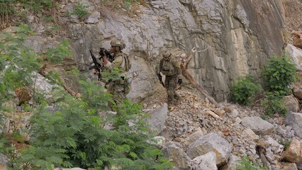 Fototapeta premium Special forces soldiers patrol through treacherous, rocky terrain during a clandestine mission, showcasing teamwork and military strategy in a hostile environment.