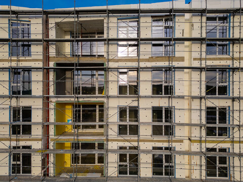 Building facade thermal insulation work with scaffolding on apartment house