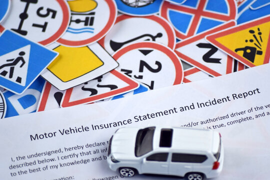Car insurance policy document and toy cars on desk.