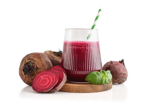 Beetroot juice in a glass with a striped paper straw, served with raw beetroot and fresh basil