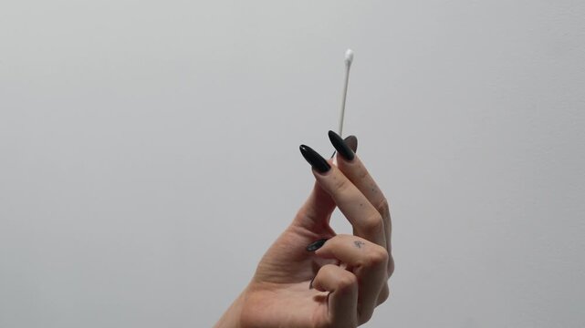 A young woman holding a cotton swab against a white background.