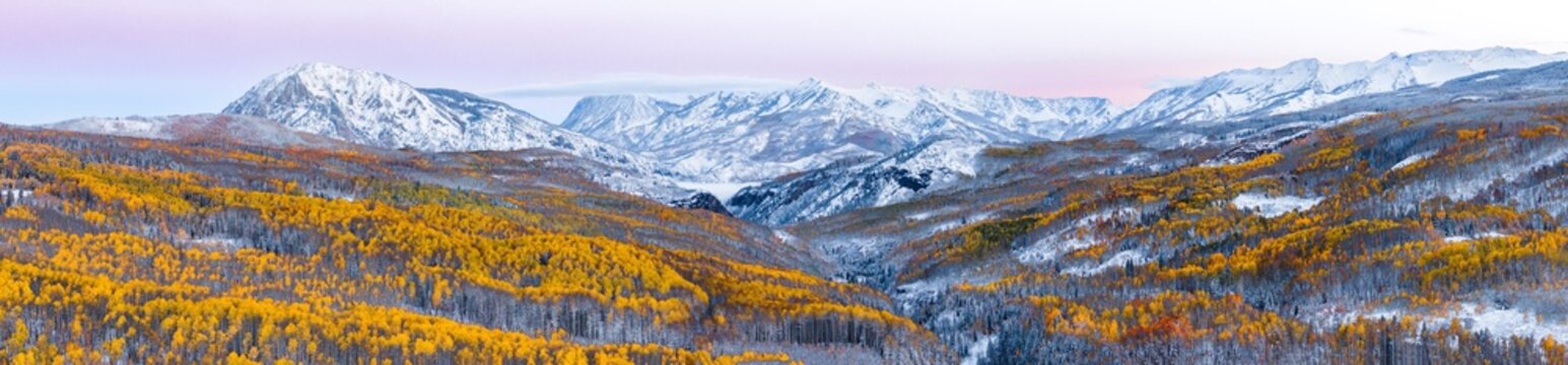 Aerial view of Kebler Pass featuring golden aspen forests dusted with early season snow beneath the snow-capped peaks of Marcellina Mountain and Ruby in Crested Butte, Colorado, United States.