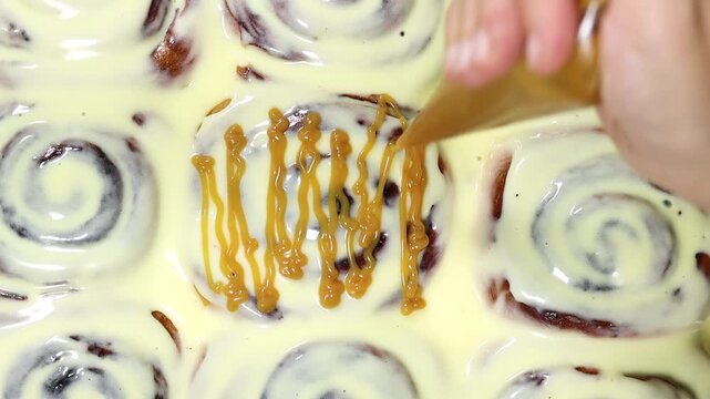 decorating Cinnamon Rolls Covered in Cream Cheese Icing with caramel