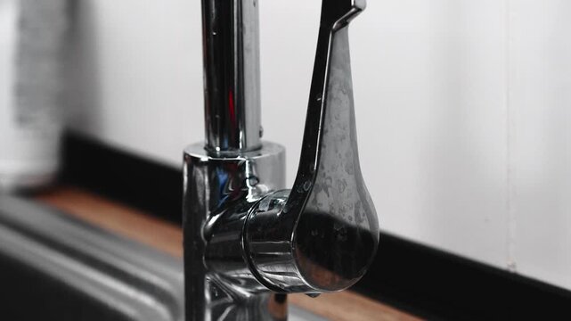 A water faucet covered in spots.
Water droplets on a metal kitchen faucet.