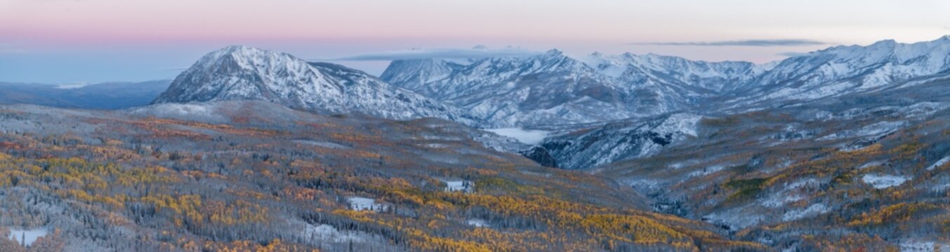 Aerial view of snow-dusted aspen forests and rugged peaks of the Ruby Range and Marcellina Mountain at sunrise in the Gunnison National Forest, Crested Butte, Colorado, United States.