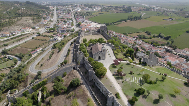 Aerial view of Montemor-o-Velho Castle with its stone walls, towers, and central church, overlooking the town and surrounding green fields in Montemor-o-Velho, Coimbra District, Portugal.