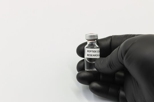 Gloved hand holding peptide compound research vial on white background