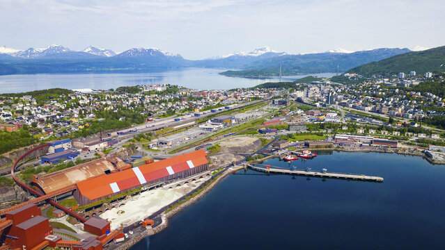 Aerial view of Narvik Harbor featuring the iron ore terminal with its red roof, industrial infrastructure, and the town nestled against the mountains and fjord in Narvik, Nordland, Norway.
