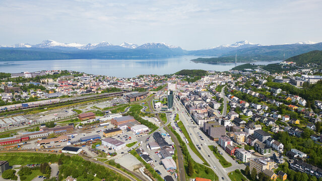 Aerial view of Narvik Harbor with the surrounding town, railway infrastructure, and the Ofotfjord framed by snow-capped mountains in Narvik, Nordland, Norway.