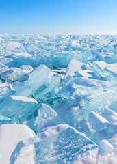 Transparent ice on Baikal lake at sunrise. Blue ice with snow against the blue sky. Baikal, Siberia, Russia. © smallredgirl