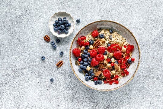 Healthy breakfast bowl with oatmeal muesli fresh berries raspberries blueberries nuts and red currants