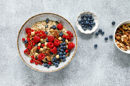 Healthy breakfast bowl with oatmeal muesli fresh berries raspberries blueberries nuts and red currants