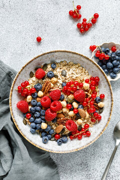 Healthy breakfast bowl with oatmeal muesli fresh berries raspberries blueberries nuts and red currants
