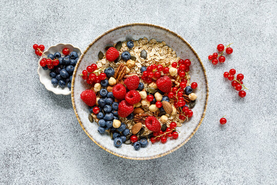 Healthy breakfast bowl with oatmeal muesli fresh berries raspberries blueberries nuts and red currants