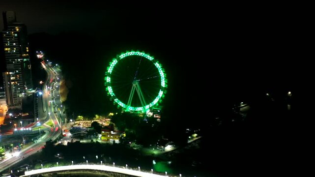 Balneario Camboriu, Santa Catarina, Brazil - June 5, 2021: Aerial view of FG Big Wheel ferris wheel lit in green at night over Barra Sul pier and skyline