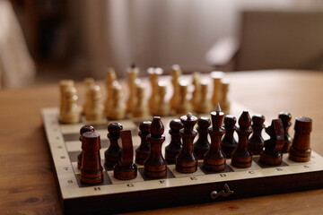 Chess board with wooden pieces arranged for game standing on table. Image suitable for advertising senior recreation, leisure club activities, and strategic business planning concepts © Seventyfour