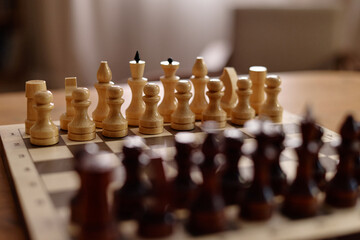 Close up shot of wooden chess pieces arranged on chessboard ready for match. Scene representing strategy, leisure activity and cognitive training for senior club marketing © Seventyfour