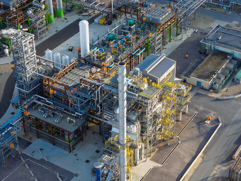 Aerial view of an oil refinery featuring complex piping, tall chimneys, and industrial structures in the United Kingdom.