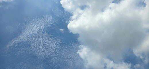 A blue sky featuring large white cloud on right and thin, rippled cloud formations—resembling fish scales or wavelets—on the left, with a combination of Altocumulus and Cumulus clouds. Sky and clouds  © Vanchuree