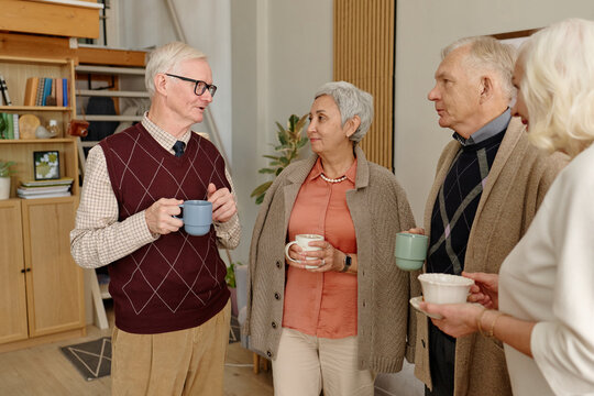 Multiethnic senior friends talking, drinking coffee together during club meeting. Image suitable for active retirement community advertising and elderly lifestyle promotion