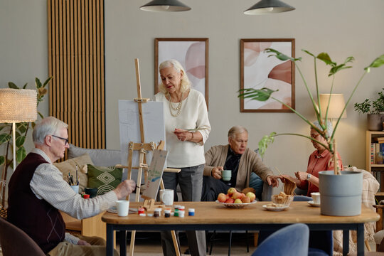 Multiethnic senior people painting on easels and knitting in community center club. Image useful for retirement leisure activities, senior healthcare and active aging concepts