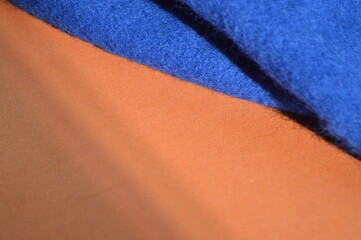 Abstract background featuring a soft blue fleece fabric layered over a smooth brown surface © Ita Ankevica