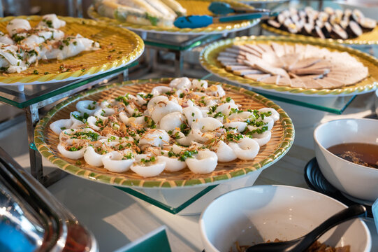 Variety of authentic Asian dishes including banh cuon and cha lua served on tiered stands at restaurant banquet. Assortment of classic Vietnamese cuisine