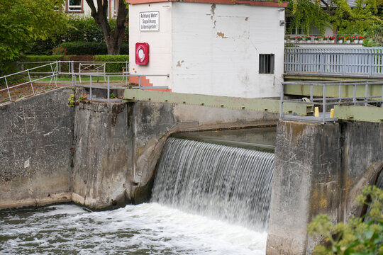 small white gatehouse building at a concrete river weir with cascading water