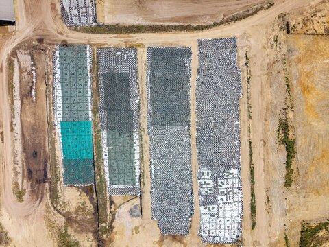 Aerial view of construction site featuring rectangular sections of geotextile erosion control mats laid out on bare earth in Philadelphia, Western Cape, South Africa.