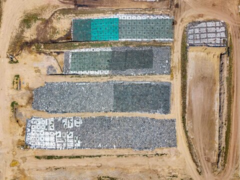 Aerial view of a construction site featuring rows of stacked tires used for erosion control, set against bare earth and dirt tracks in Philadelphia, Western Cape, South Africa.