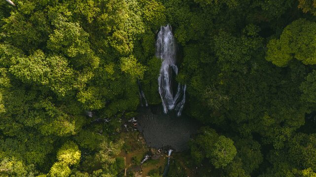 Aerial view of Tegenungan Waterfall surrounded by lush tropical forest and greenery in Sukawati, Bali, Indonesia.