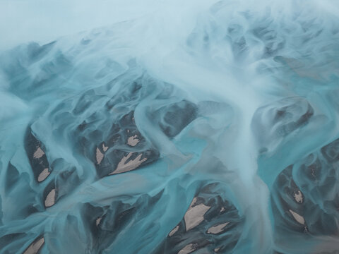Aerial view of Knik River with its intricate glacial braided channels, silt-laden turquoise water, and gravel bars in Knik River, Alaska, United States.
