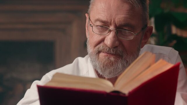 Concentrated focused Caucasian old senior business man reading book textbook at home library elderly professor in glasses aged businessman read literature male academic enjoying story at home office