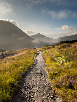 West Highland Way trail on the moors in the highlands of Scotland with the town of Bridge of Orchy and Beinn Odhar and Beinn Dorain mountains in the distance